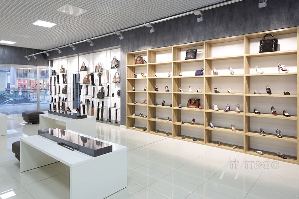 Un negozio di borse moderno e luminoso, con scaffali ordinati pieni di borse varie e una zona salotto centrale, caratterizzato da arredamenti contract.