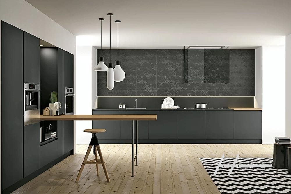 Interni di una cucina moderna con mobili grigio scuro, lungo bancone, elettrodomestici da incasso e pavimenti in legno chiaro, che mostrano una cucina dal design personalizzato.